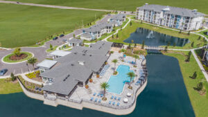 overhead view of comunity center and pool surrounded by lake and apartments at champions vue by park square homes kimaya