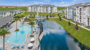 blue lake surrounded by champions vue apartments next to a pool and community center at champions vue in davenport florida
